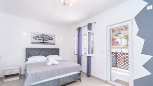 Un dormitorio con cama, mesita de noche, ventana con cortinas y vistas al exterior.