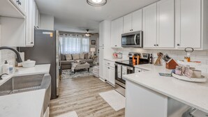 Une cuisine moderne avec des meubles blancs, des appareils en acier inoxydable et un îlot central.