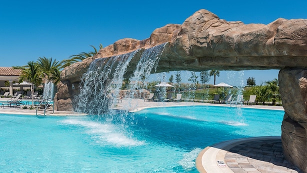 Une piscine agrémentée d’une cascade, de chaises longues et de palmiers.