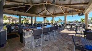 Une terrasse extérieure dotée d’un bar, de coins salon et offrant une vue sur la piscine.