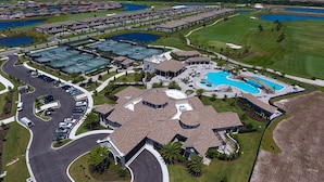 Vue aérienne d’un complexe hôtelier comprenant un grand bâtiment central, plusieurs piscines et un parcours de golf.