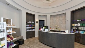 Un espace d’accueil moderne doté d’un comptoir incurvé, d ’étagères présentant des produits, d’un coin salon et d’un mur décoratif.