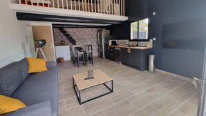 A modern loft apartment with a loft bedroom, a kitchen with dark cabinetry, and a dining area. - House 7 pers (Fos-sur-Mer)