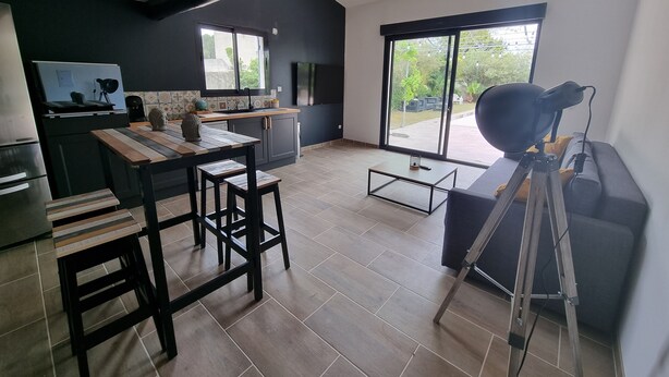A modern kitchen with a dining area, large windows, and a tripod in the corner. - House 7 pers (Fos-sur-Mer)