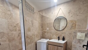 A bathroom with a shower, sink, toilet, and a small trash bin. - House 7 pers (Fos-sur-Mer)