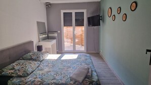 A bedroom with a bed, a desk, a chair, a TV, and a sliding door to the outside. - House 7 pers (Fos-sur-Mer)