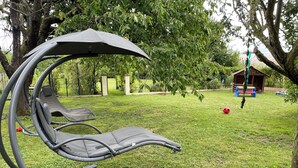 A garden with a swing set, a hammock, and a small wooden structure. - Sélestat Beautiful house with large wooded garden Meublé tourisme Les Tulipes 3⭐ (Sélestat)