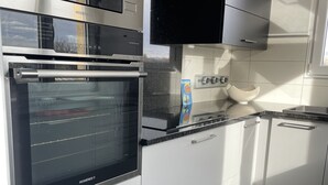 A modern kitchen with stainless steel appliances, white cabinetry, and a tiled backsplash. - Sélestat Beautiful house with large wooded garden Meublé tourisme Les Tulipes 3⭐ (Sélestat)