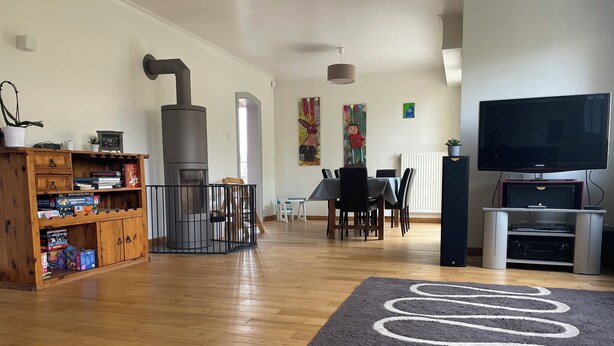 A spacious living room with a wooden entertainment unit, a large flat-screen TV, and a cozy fireplace. - Sélestat Beautiful house with large wooded garden Meublé tourisme Les Tulipes 3⭐ (Sélestat)