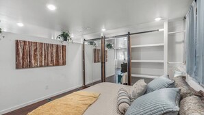 Une chambre à coucher avec un grand lit, une armoire, un miroir et une œuvre d’art accrochée au mur.