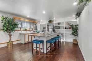 A modern kitchen with a central island, bar stools, and built-in shelves.