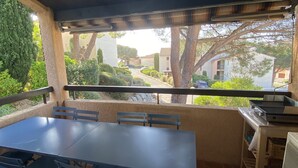 Une terrasse extérieure avec une grande table et des chaises, un barbecue et une vue sur le quartier.