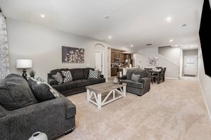 A spacious living room with a sofa, coffee table, and a dining area with chairs.