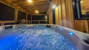 Un jacuzzi con chorros de agua, paredes de madera y un techo con vigas a la vista.