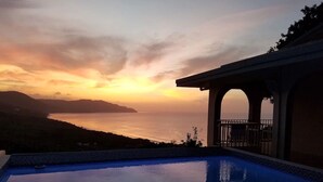 Una piscina con vista al océano y un atardecer.