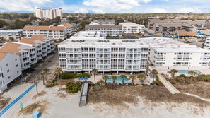 A multi-story hotel with balconies, a swimming pool, and a beach area. - DISCOUNTED Sept 9th-12th Still Available! Oceanfront Condo STEPS FROM BEACH! (Myrtle Beach)