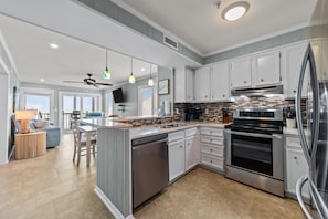 A modern kitchen with white cabinets, stainless steel appliances, and a large island. - DISCOUNTED Sept 9th-12th Still Available! Oceanfront Condo STEPS FROM BEACH! (Myrtle Beach)