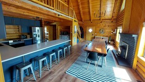 A spacious log cabin interior with a large kitchen, dining area, and a cozy fireplace. - Large Reunion Cabin By Lake And National Parks! (Panguitch)