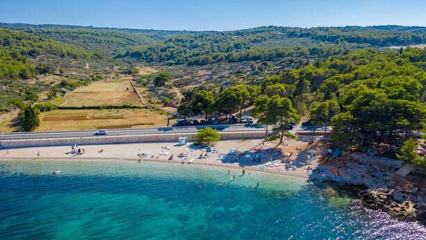 A coastal beach with clear turquoise waters, a sandy shore, and a backdrop of green hills. - Villa Serenity - Silence, view and heated pool by MyWaycation (Supetar)