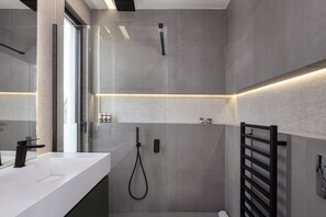 A modern bathroom with a white vanity, a glass shower enclosure, and a towel rack. - Sounio Panoramic Loft (Lavreotiki)