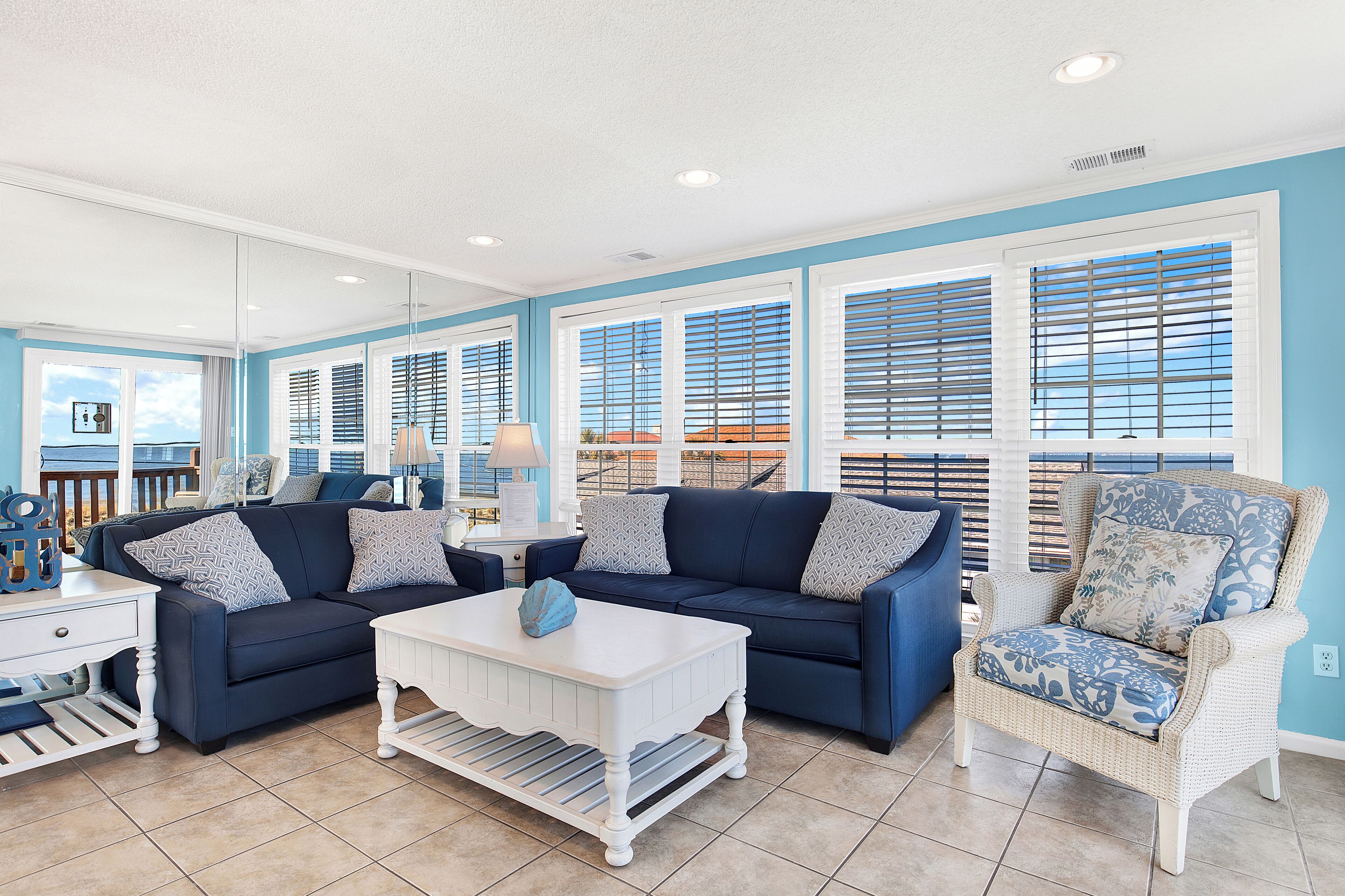 A living room with a blue sofa, white coffee table, and wicker chair.