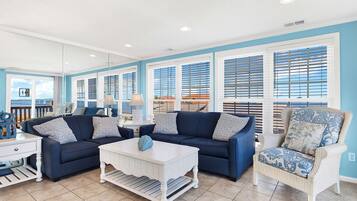 A living room with a blue sofa, white coffee table, and wicker chair.