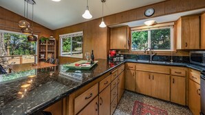 A modern kitchen with wooden cabinets, a granite countertop, and pendant lighting. - Mystic Meadow ~ Sweet Cabin + Meadow Views (Shaver Lake)