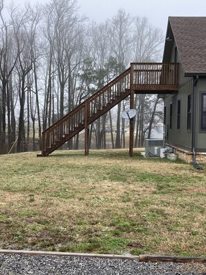 A wooden staircase leading to a deck on a house with a satellite dish.
