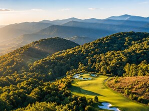 Un parcours de golf comportant plusieurs trous, entouré d’une forêt dense et de collines ondoyantes.