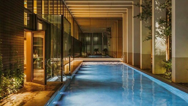 Ein modernes Hallenbad mit Glaswänden, Holzboden und einer langen, schmalen Form.