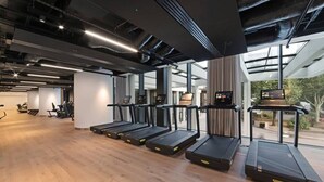 Ein modernes Fitnessstudio mit Laufbändern, Fahrrädern und einem großen Fenster, das viel Tageslicht hereinlässt.