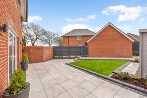 Enjoy a serene outdoor space with a paved patio, lawn, and brick wall.
