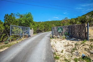 A rural road leading to a fenced property with a sign indicating it is Antler Ranch.