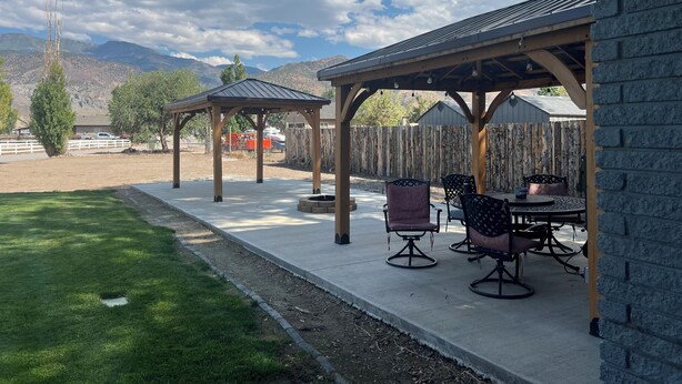 A covered patio area with outdoor furniture, a pergola, and a view of mountains in the background. - Beautiful Monroe Home on Paiute trail by Mystic Hot Springs ATV, flyers landing (Monroe)