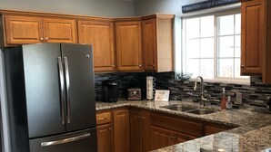 A modern kitchen with wooden cabinets, a stainless steel refrigerator, a granite countertop, and a window with a view. - Beautiful Monroe Home on Paiute trail by Mystic Hot Springs ATV, flyers landing (Monroe)