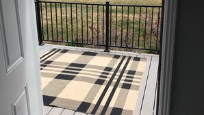 A wooden deck with a checkered mat, a black metal railing, and a view of a rural landscape with mountains and a white fence. - Beautiful Monroe Home on Paiute trail by Mystic Hot Springs ATV, flyers landing (Monroe)