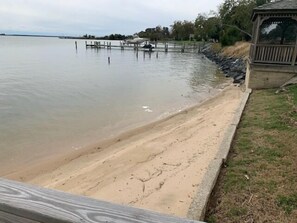 A sandy beach with a wooden deck and a gazebo.