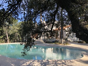 A swimming pool surrounded by trees and a building with a tiled roof. - A villa surrounded by nature, cicadas, and pine trees (Espira-de-l'Agly)