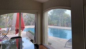 Una stanza con vista su una piscina, arredi da esterno e una zona patio.