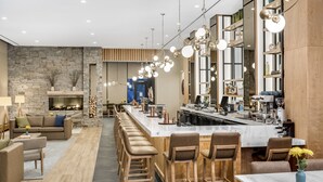 A modern kitchen with a central island, bar stools, and a stone wall. - Lockwood Hotel (Waterville)
