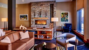 A modern living room with a stone fireplace, leather sofa, and a blue armchair. - Lockwood Hotel (Waterville)