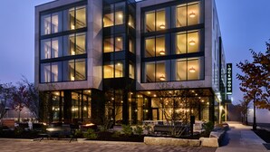 A modern hotel with a glass facade, outdoor seating area, and a well-lit entrance. - Lockwood Hotel (Waterville)