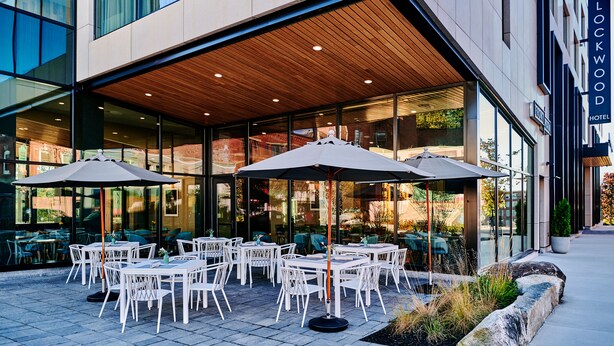 An outdoor seating area with tables and umbrellas at a hotel. - Lockwood Hotel (Waterville)