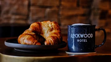 A croissant on a plate next to a mug with "Lockwood Hotel" written on it.