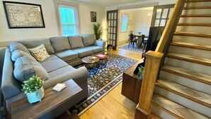 A living room with a sectional sofa, a coffee table, a rug, a staircase, and a dining area in the background. - Fully Fenced & Dog Friendly - Minutes to Liberty Mtn & Gettysburg (Gettysburg)