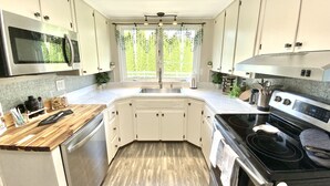 A modern kitchen with white cabinets, a stainless steel microwave, a black stove, and a wooden countertop. - Fully Fenced & Dog Friendly - Minutes to Liberty Mtn & Gettysburg (Gettysburg)