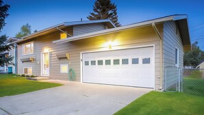 Une maison moderne à deux étages, dotée d’un garage, d’une pelouse bien entretenue et surplombant un ciel dégagé.