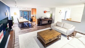 Un salon moderne avec une table basse en bois, un canapé blanc et un coin repas comprenant une table et des chaises.
