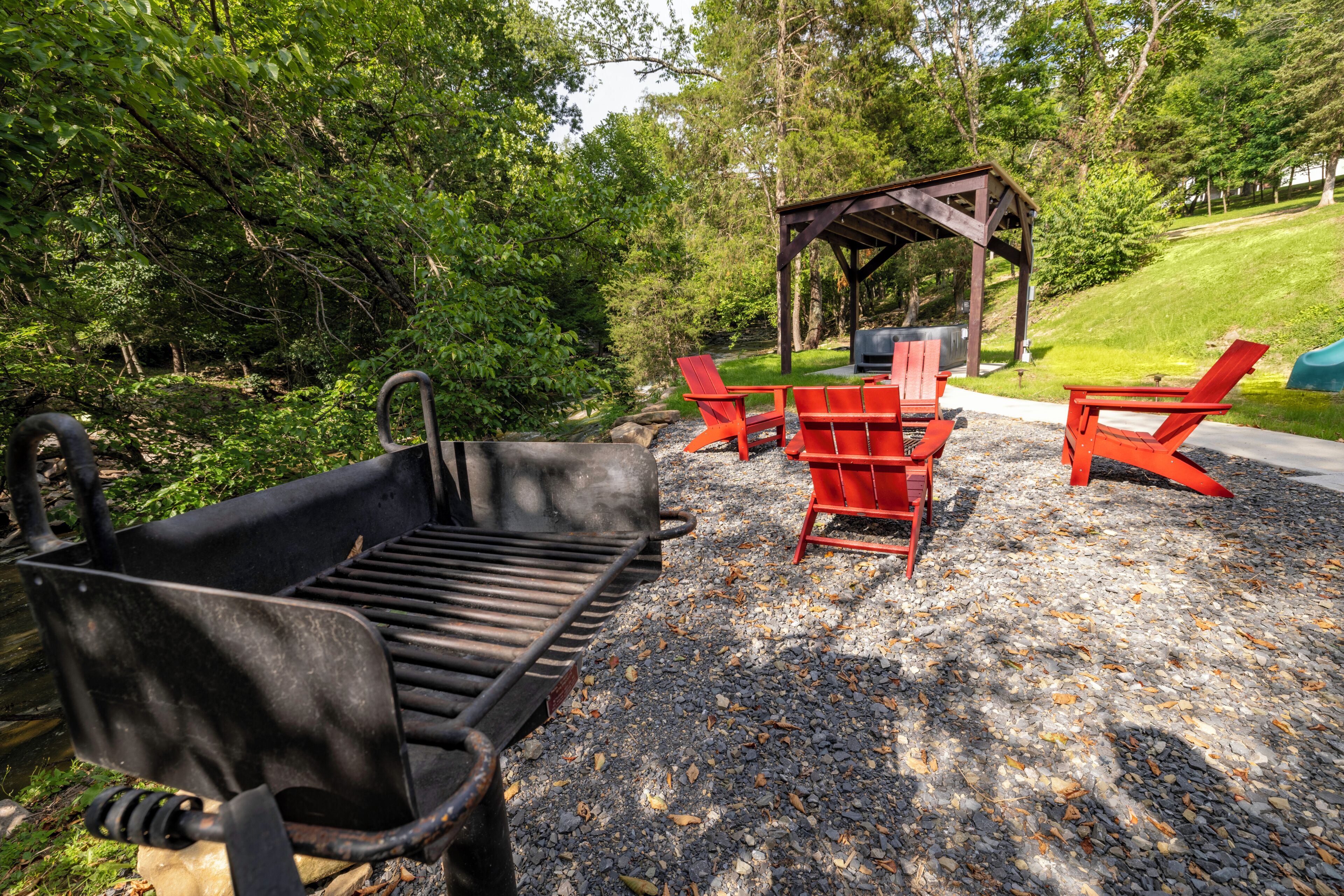 Un barbecue, des chaises Adirondack rouges et un gazebo en bois, le tout installé dans un parc.