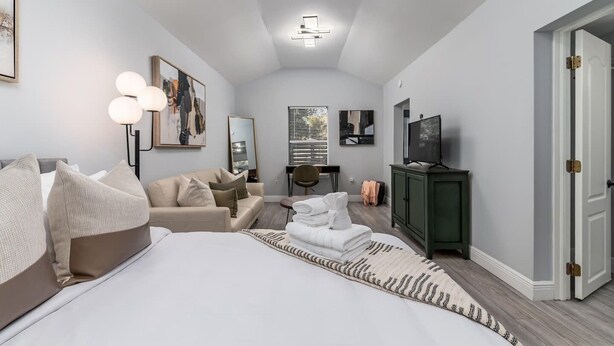 Una habitación de hotel moderna con una cama grande, un sofá, un escritorio y una televisión.